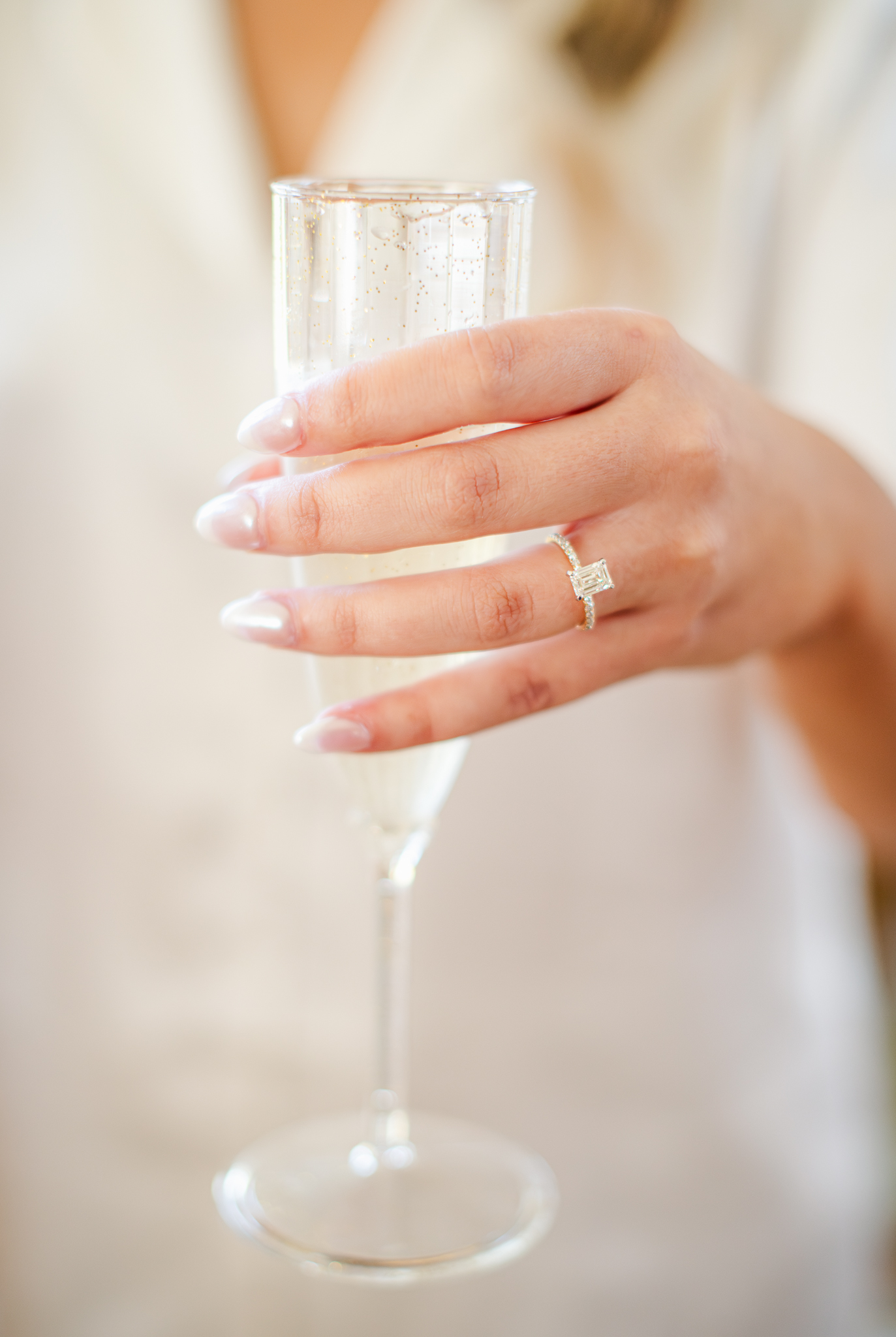 Bride holding a champagne glass showing her engagement ring on wedding day