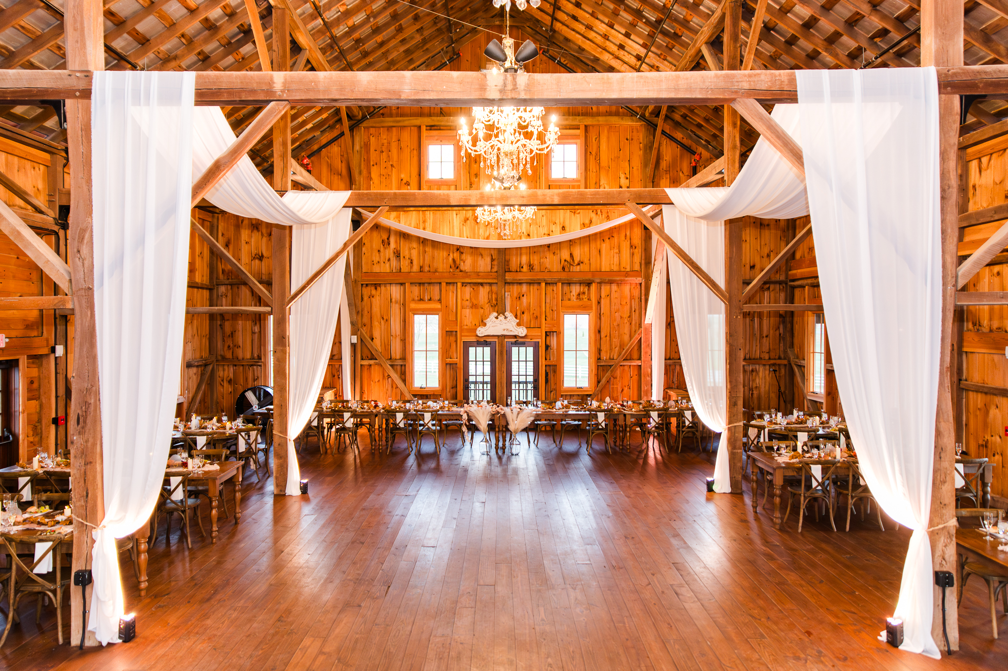 The gorgeous red barn reception hall featuring their chandeliers