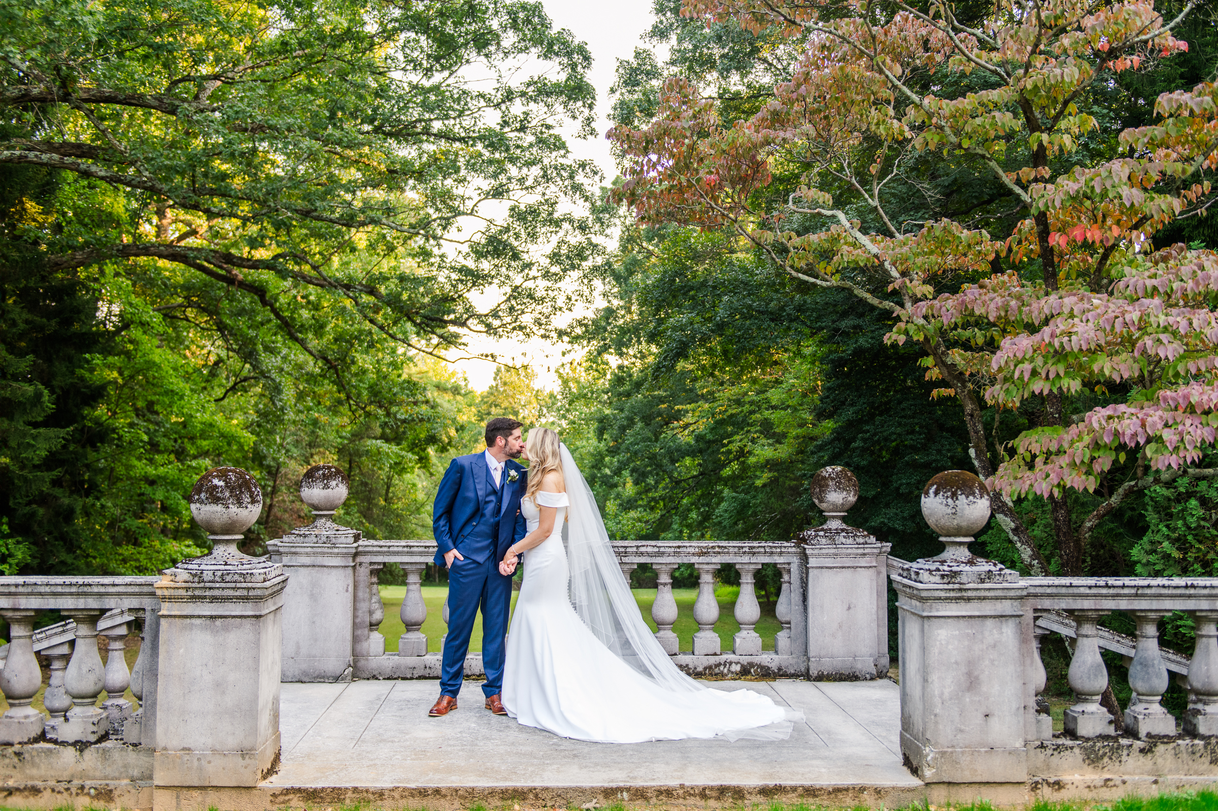 A sweet kiss between the bride and groom on the elegant stone staircase leading to the formal gardens at Strong Mansion in Frederick, Maryland