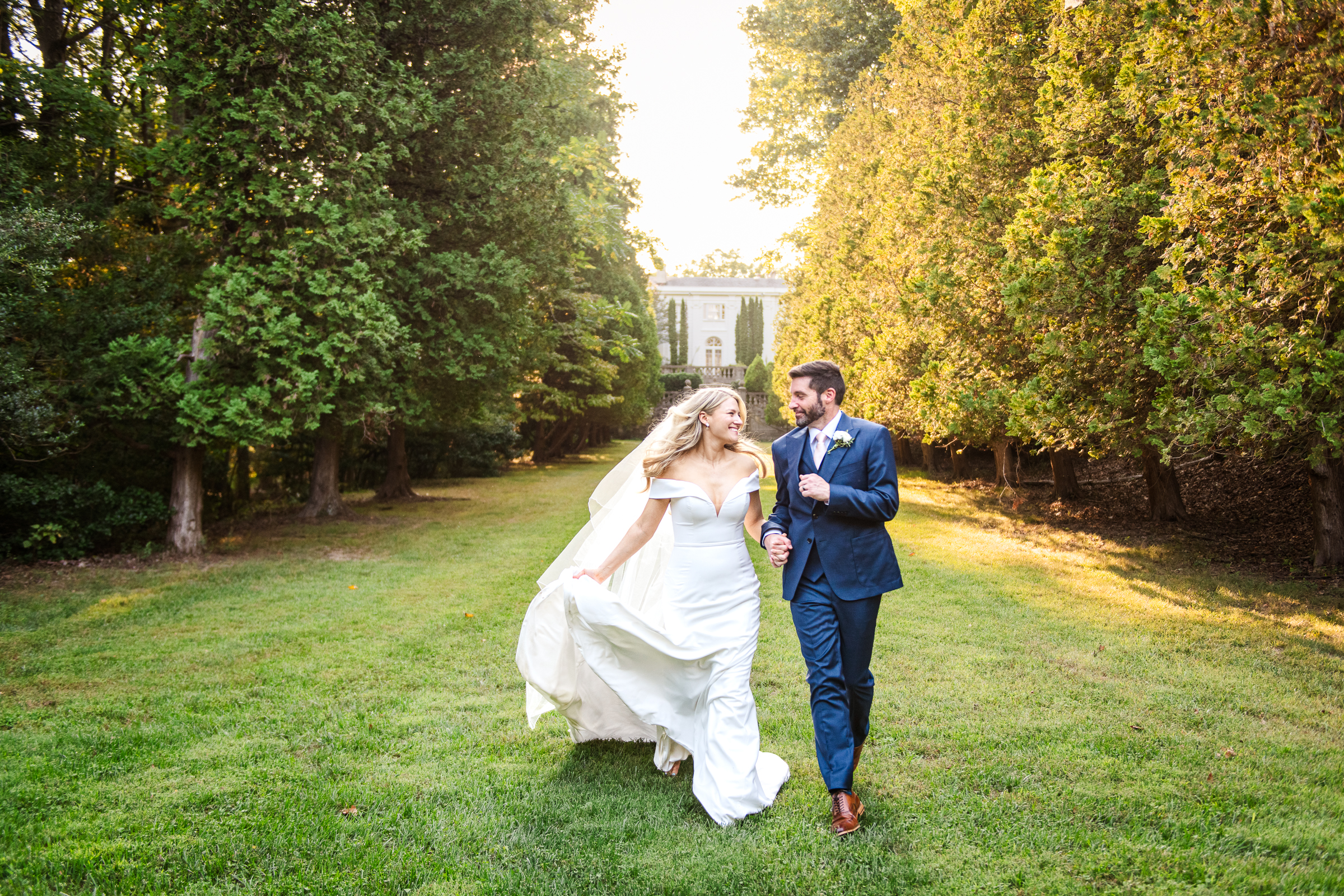 A newlywed couple joyfully run together through Strong Mansion's formal gardens
