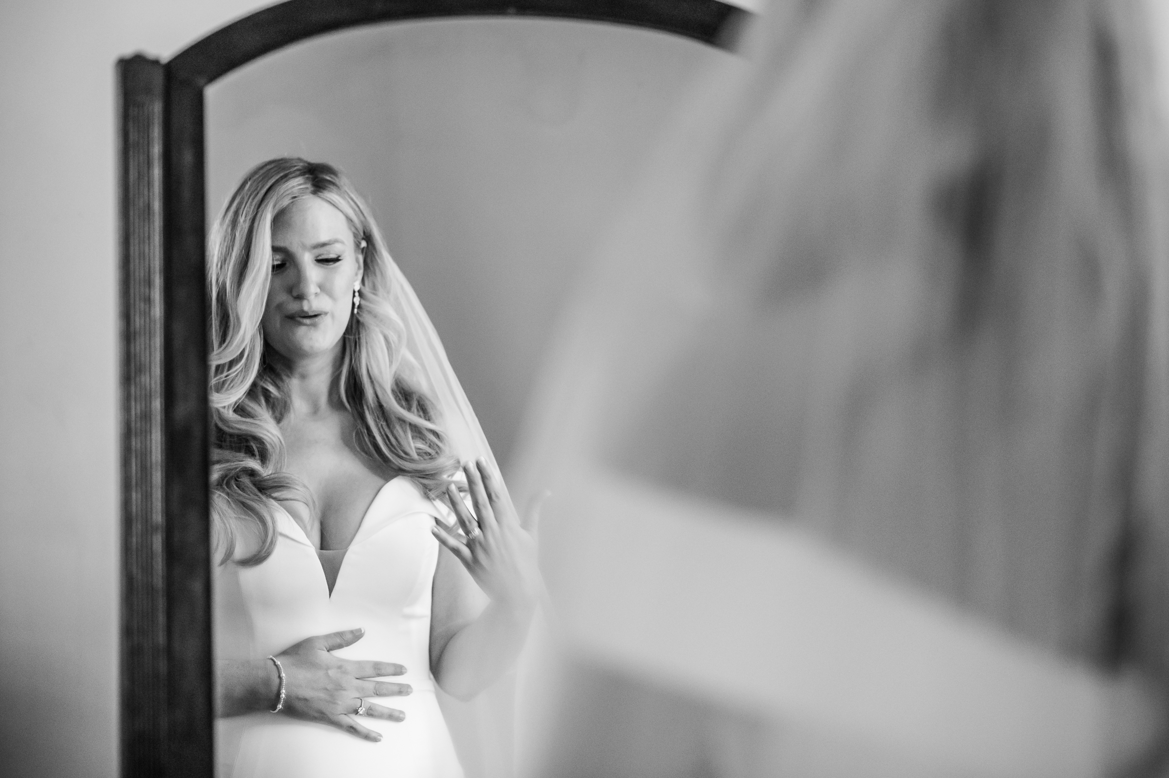 Black and white emotional candid of a bride getting emotional while looking in the mirror before her wedding ceremony