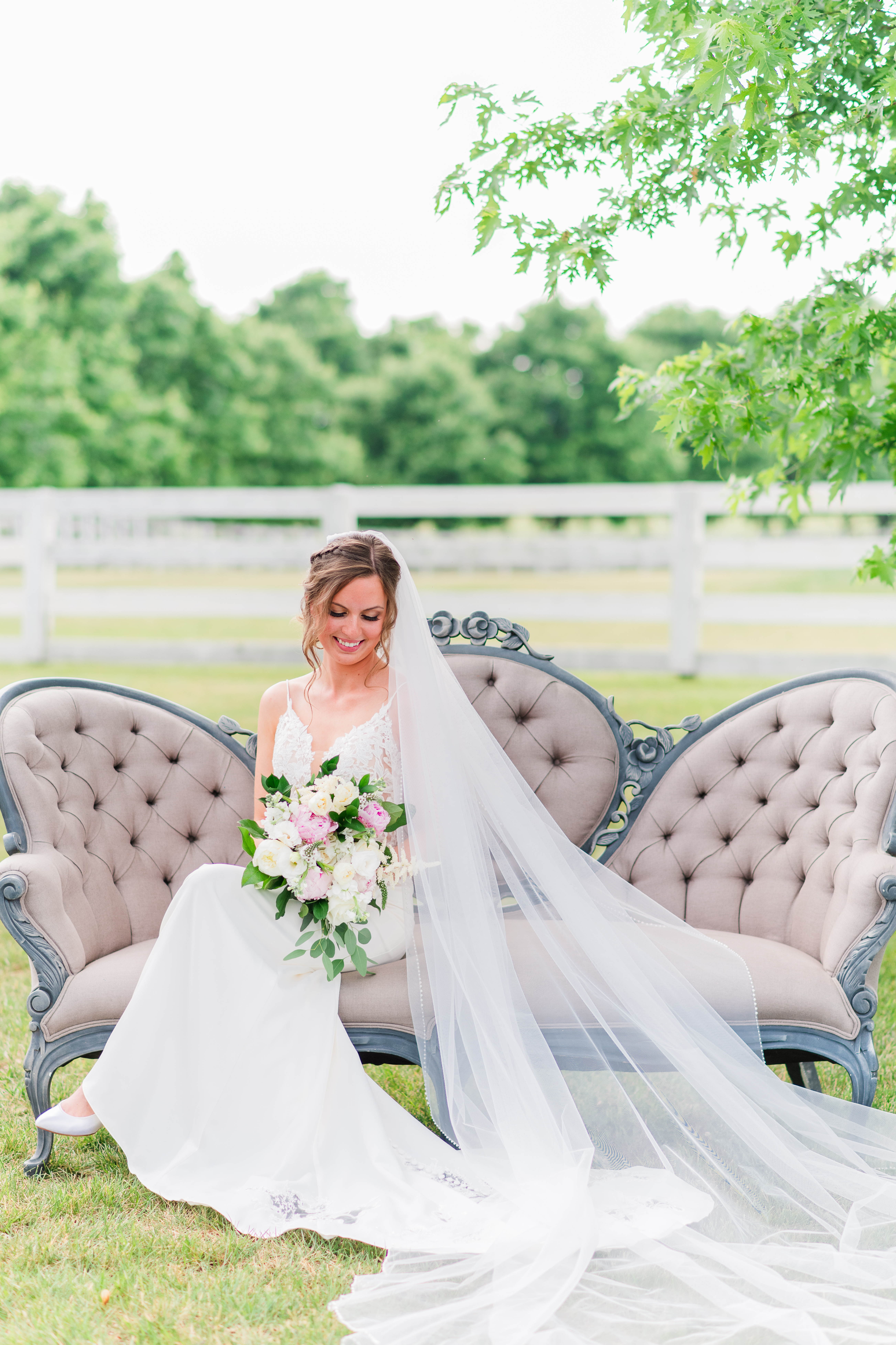 Bride holding bouquet while seated on vintage couch at Bluebird Manor