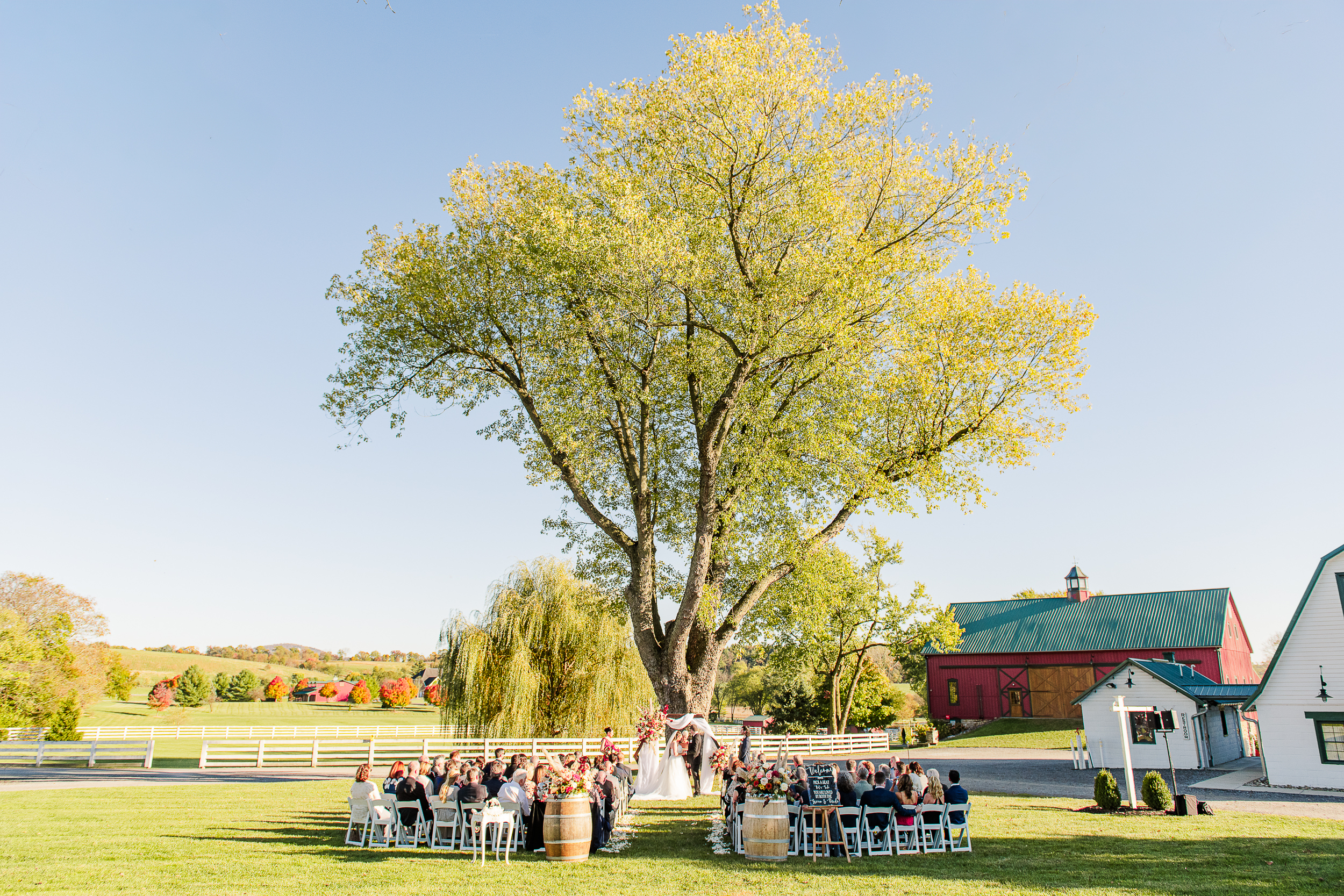 Fall wedding ceremony at Bluebird Manor with red barn in background