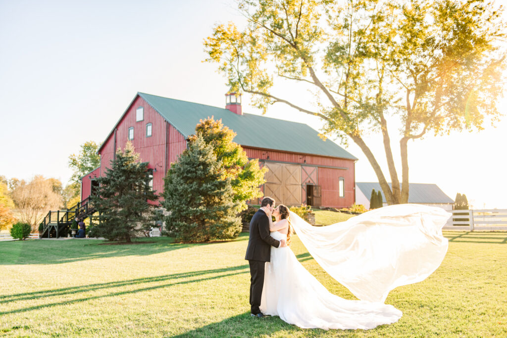 Golden hour fall wedding portrait in front of the red barn at Bluebird Manor