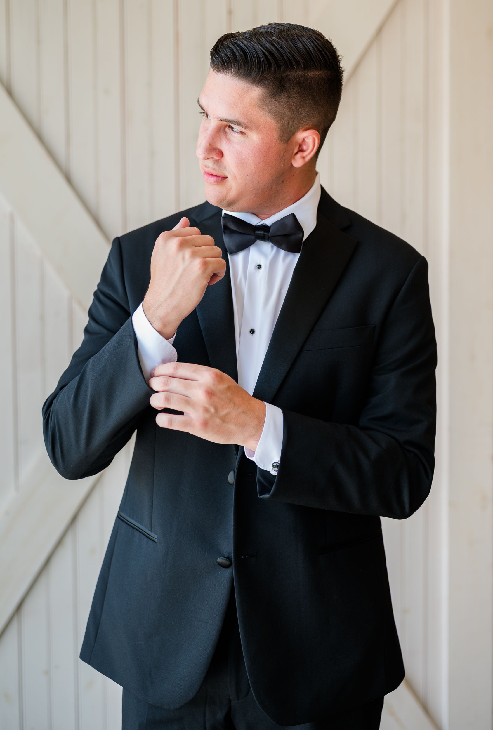 Groom adjusting cufflinks in tuxedo at Bluebird Manor