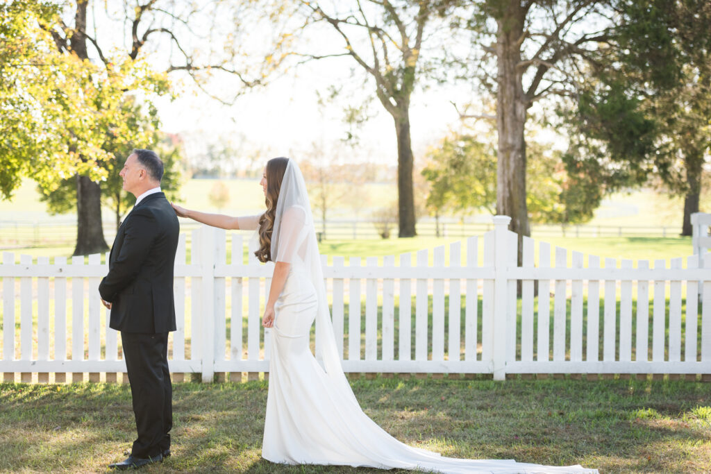 Bride tapping dad on shoulder during outdoor daddy daughter first look
