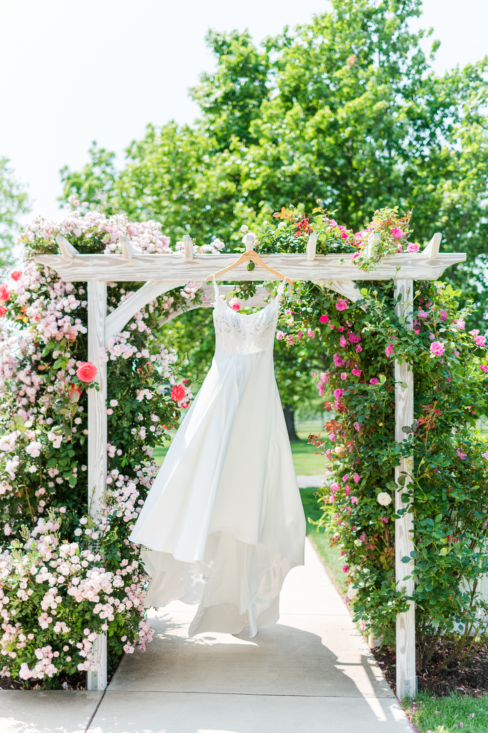 Wedding dress hanging on the rose arbor at Bluebird Manor
