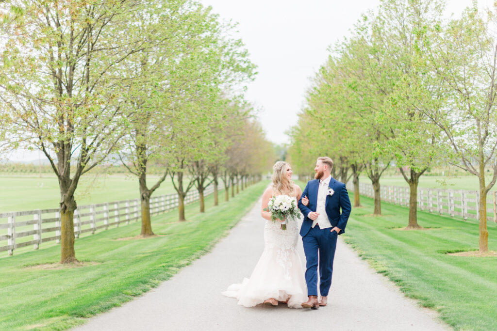 Bride and groom walking along the tree-lined driveway at Bluebird Manor in Frederick Maryland