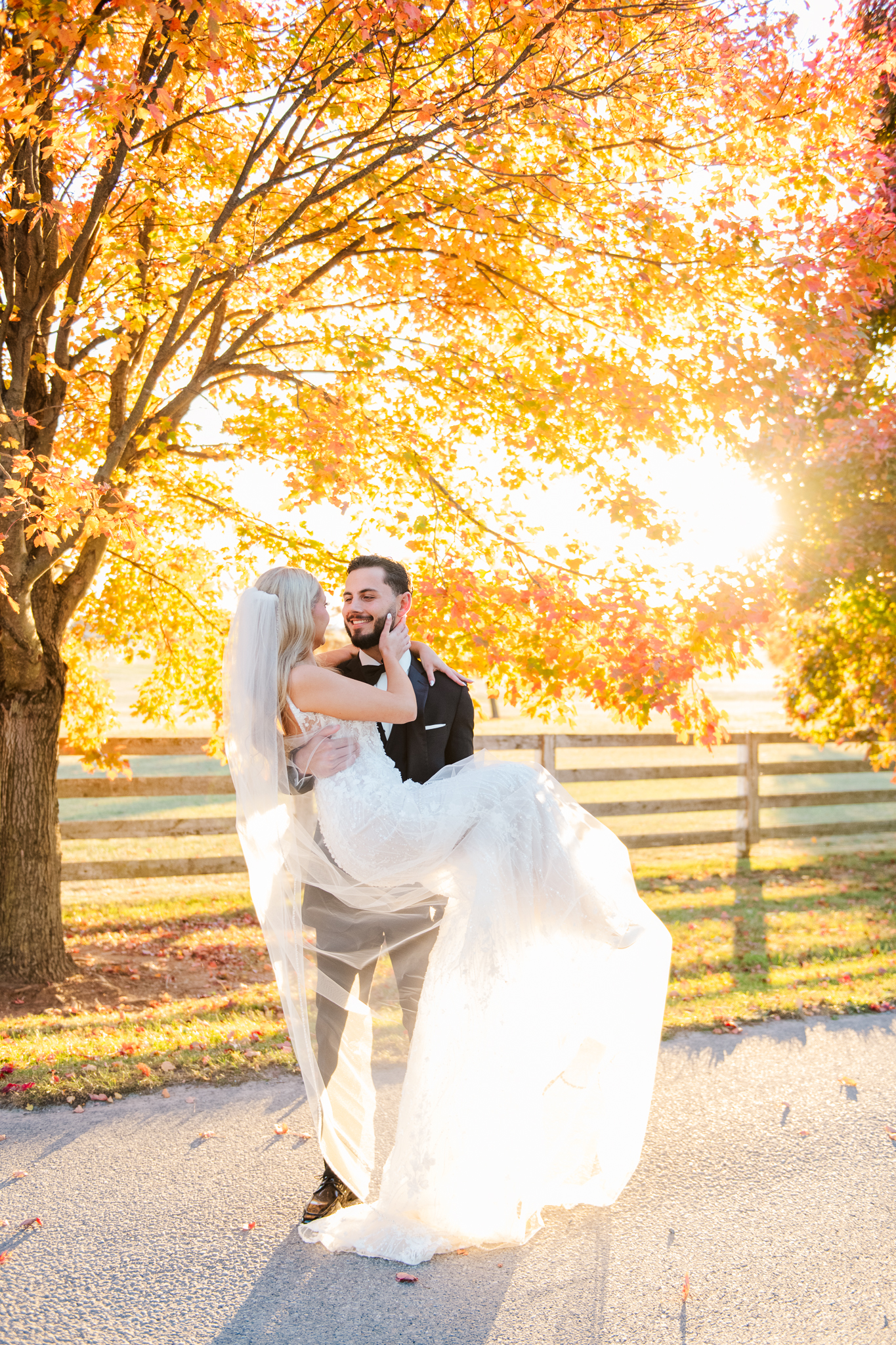 Bride and groom under vibrant fall foliage at Bluebird Manor during golden hour