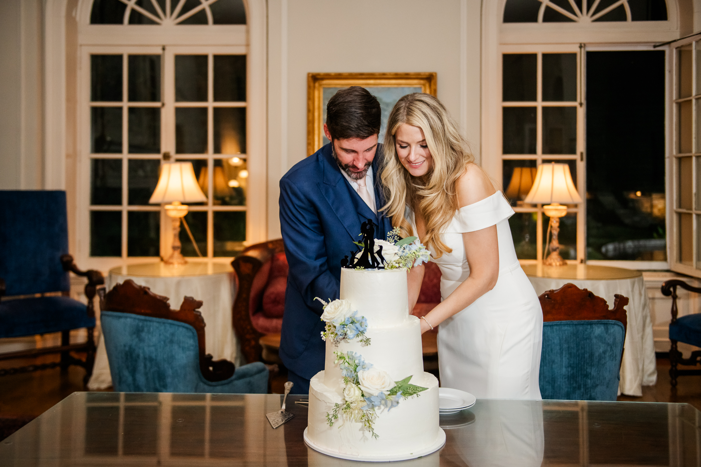The bride and groom cutting their three tiered wedding cake inside the stunning Strong Mansion ballroom. 