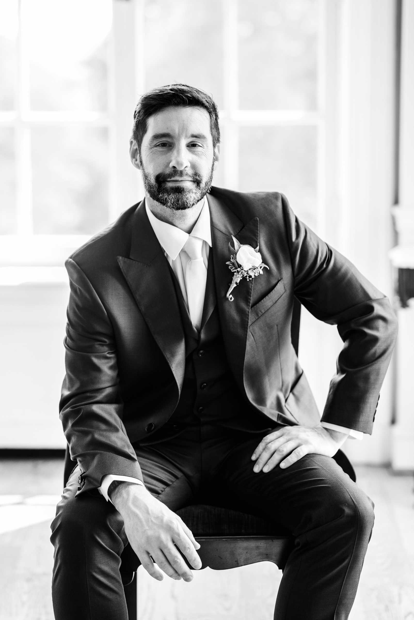Classic black and white groom pose by a window inside the historic Strong Mansion in Frederick Maryland.