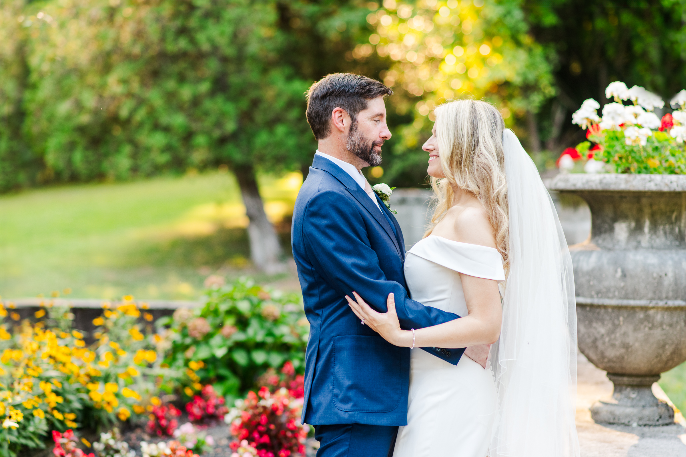 Bride and groom embrace in front of the European gardens of Strong Mansion