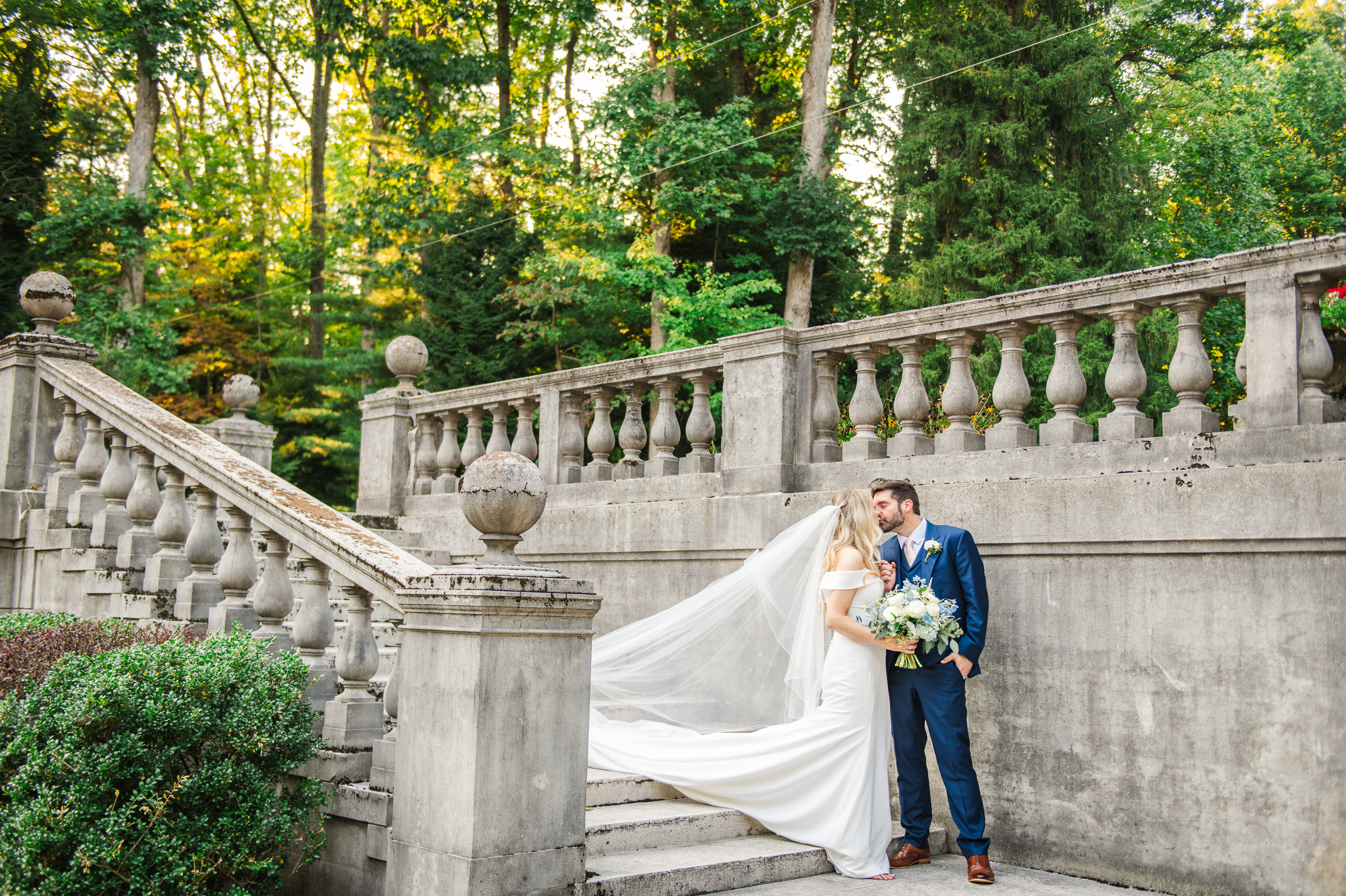 Bride and groom share a kiss on the stairs of the formal gardens of Strong Mansion during a sunset portrait session by Mary Sarah Photography.
