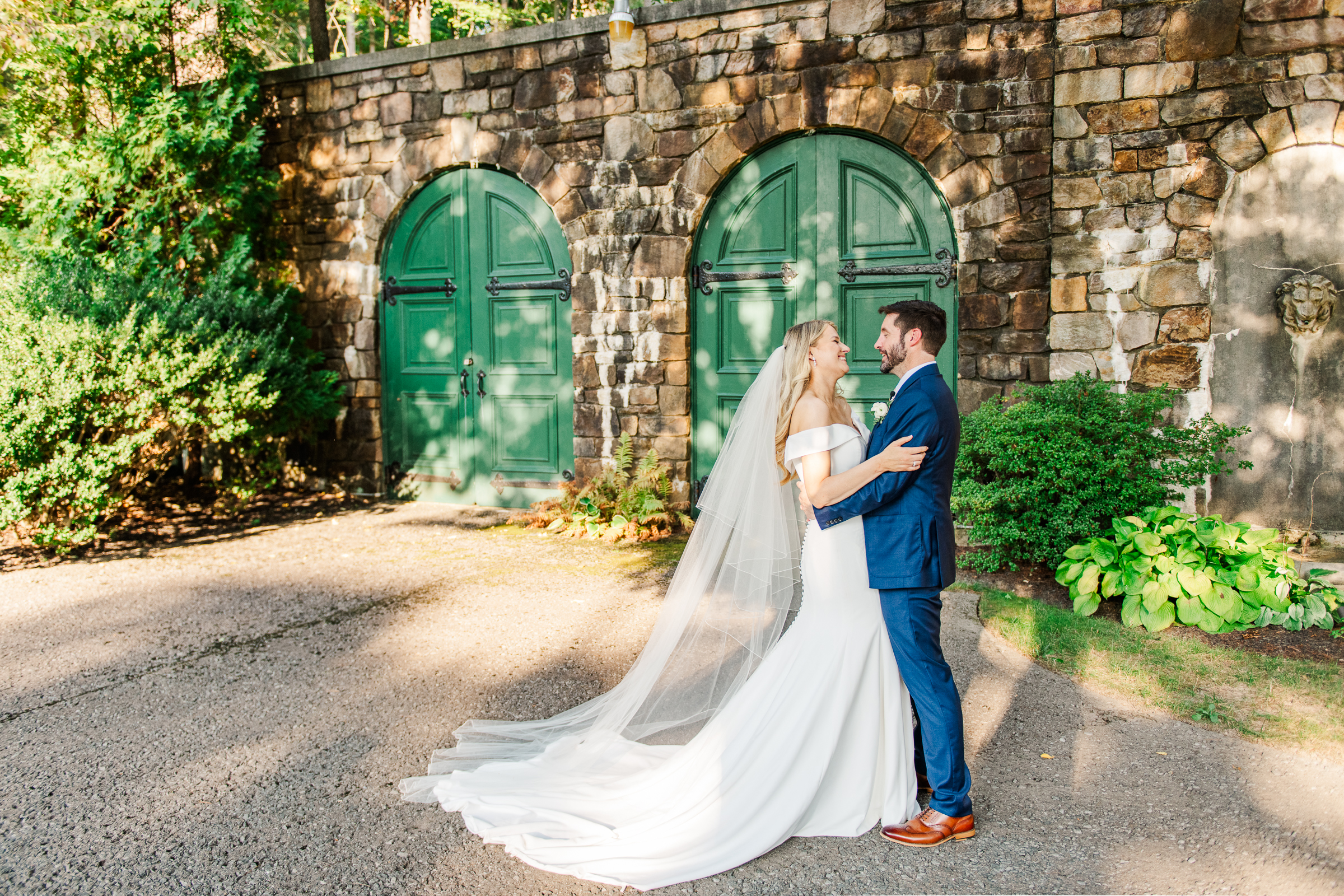 Bride and groom embrace in front of the old world green doors found in the European gardens of Strong Mansion