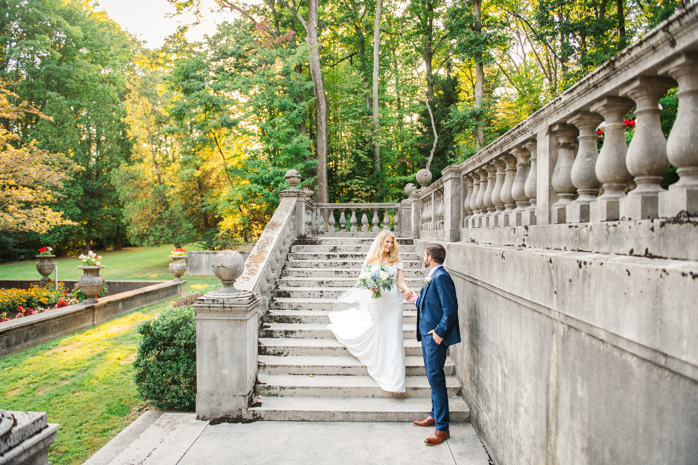 Groom leads his bride down the stairs of the formal gardens of Strong Mansion during a sunset portrait session by Mary Sarah Photography.