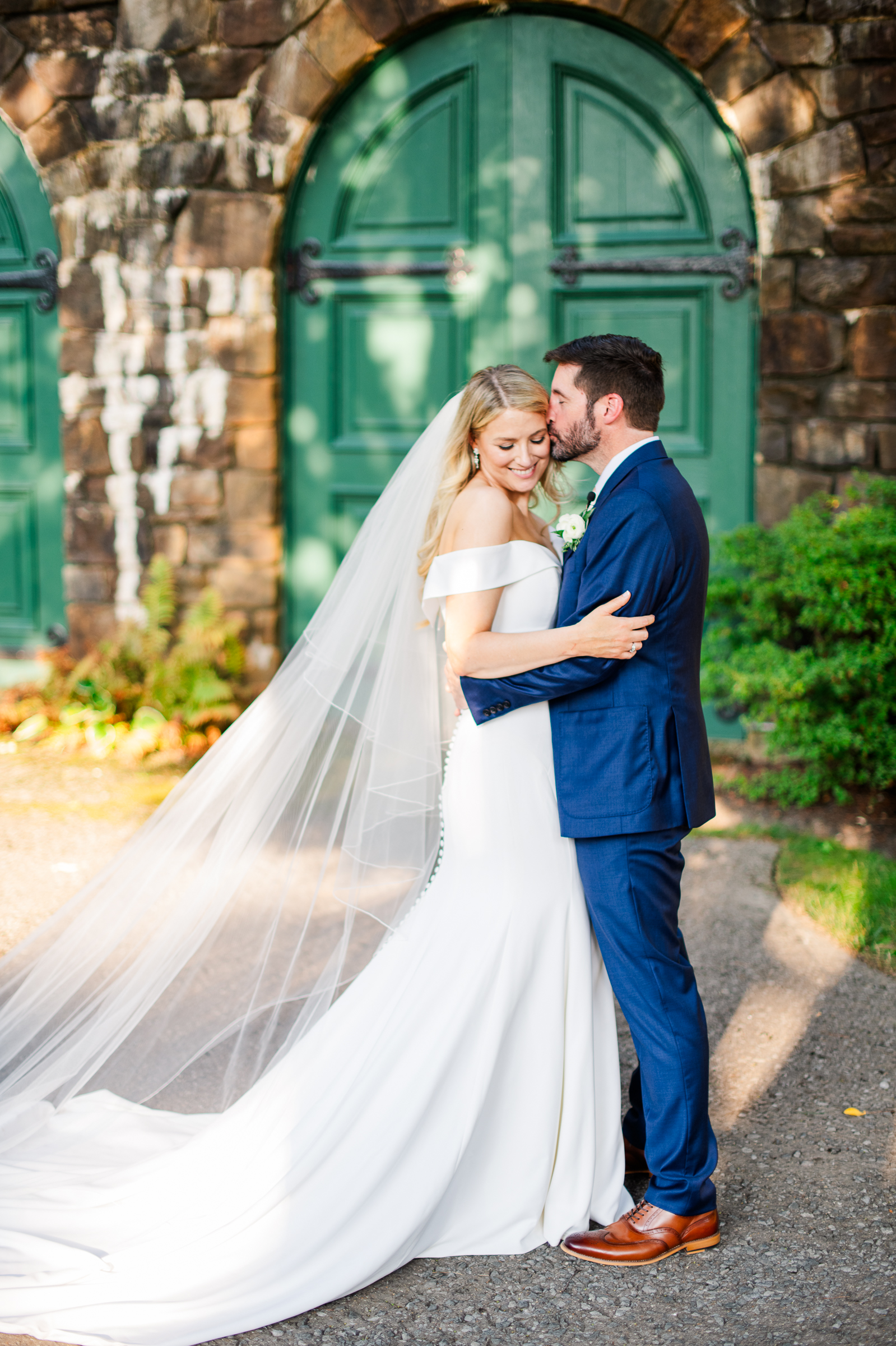 A stunning bride and groom portrait posing against the classic stone architecture and green doors of Strong Mansion.