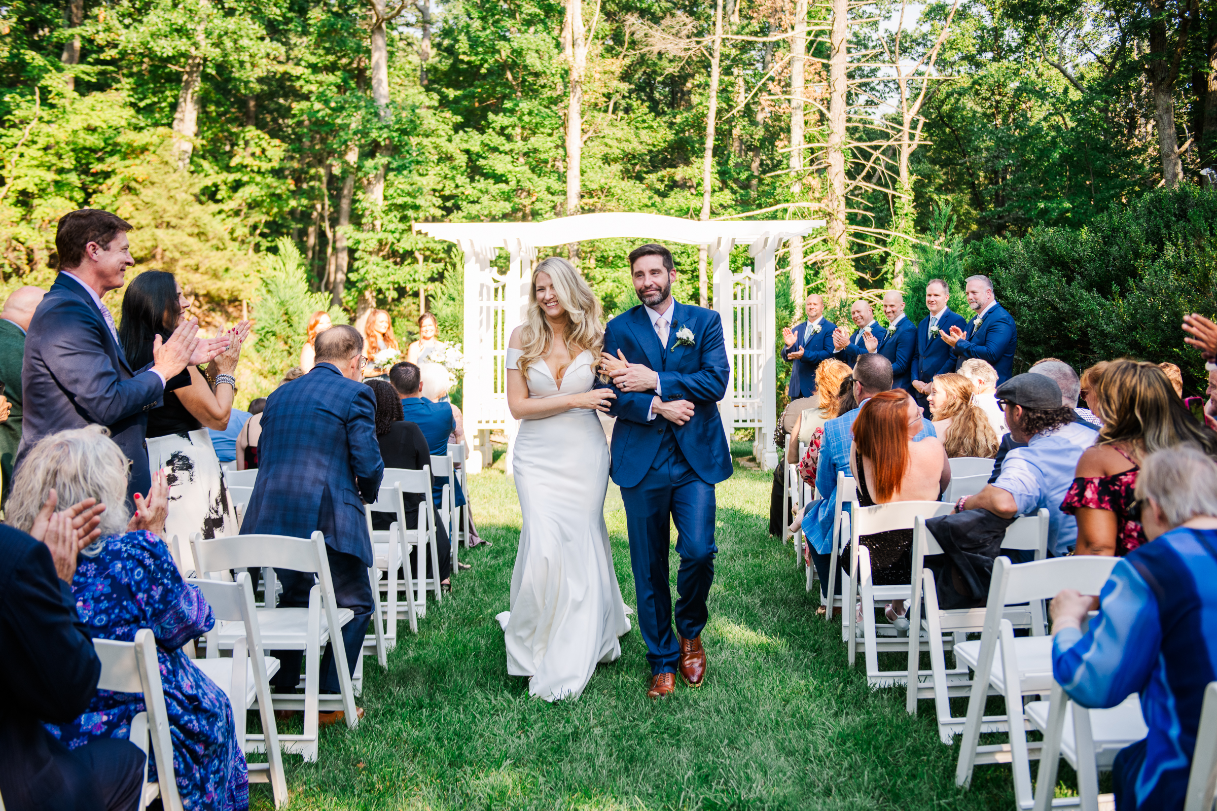 Bride and groom joyfully process down Strong Mansions aisle surrounded by a beautiful wooded setting