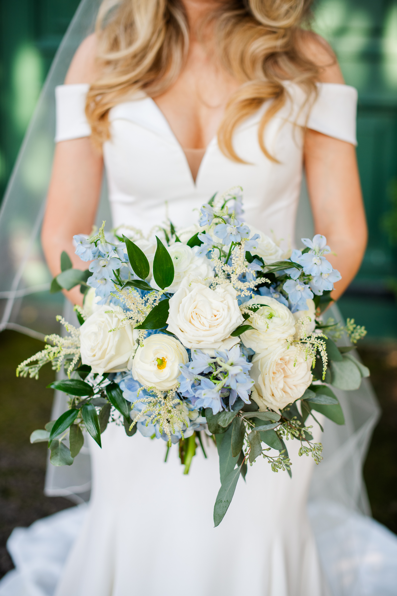 A stunning portrait of a bride holding a luxury bouquet featuring white garden roses with blue accents