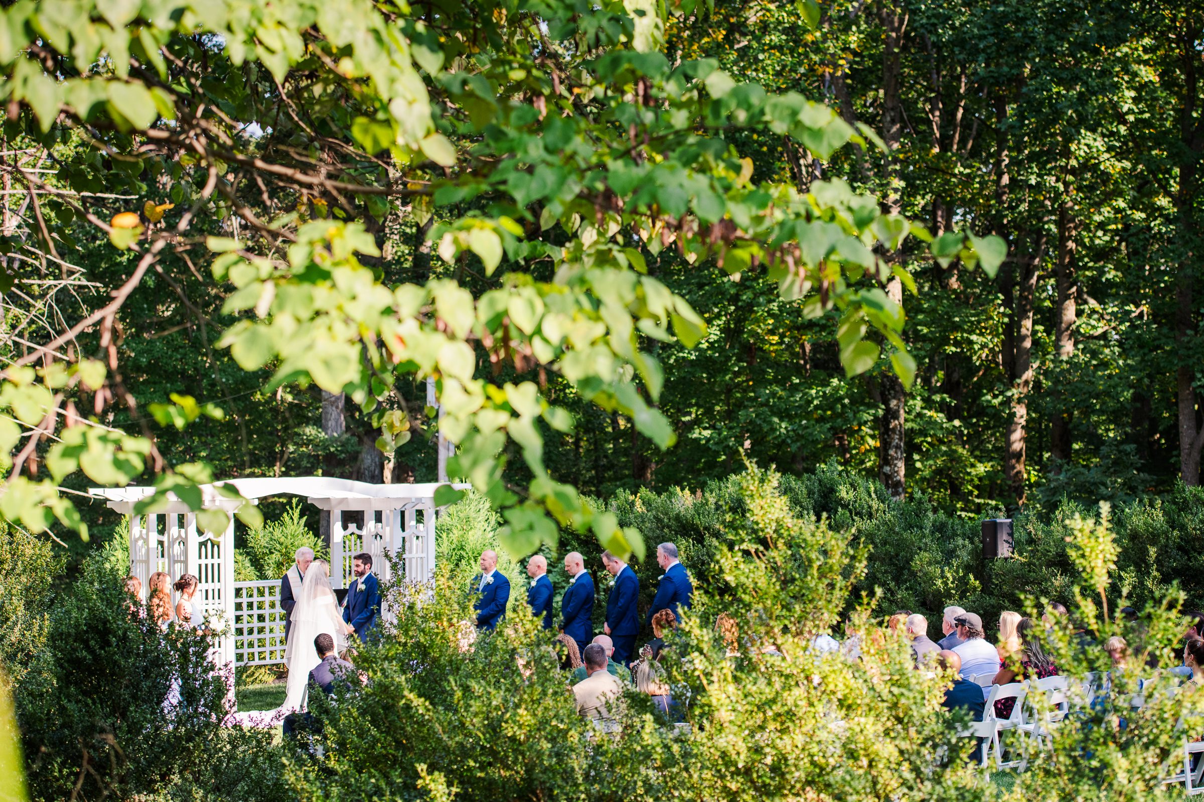A romantic wooded wedding ceremony taking place at Strong Mansion, artistically taken from the side.