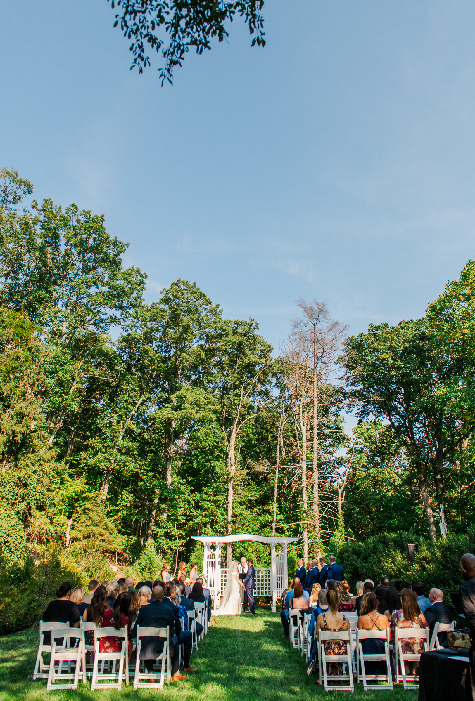 A romantic wooded wedding ceremony taking place at Strong Mansion.